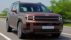 an suv driving down the road with trees in the background