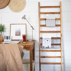 a wooden ladder leaning up against a wall next to a desk with baskets on it