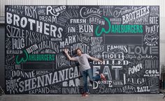 a man standing in front of a chalkboard wall with words all over it that say brothers and daughters