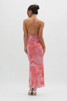 the back of a woman wearing a pink and white tie dye dress with halter neckline