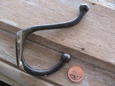 a close up of a metal hook on a wooden door with a penny in the background