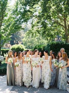 a group of women standing next to each other wearing dresses and holding bouquets in their hands