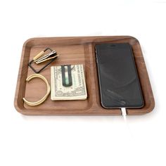 a wooden tray with a cell phone, wallet and money on it