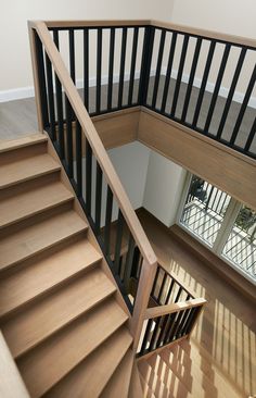 an overhead view of a wooden staircase with black railings