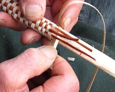 two hands are working on a piece of wood that is connected to an electrical wire