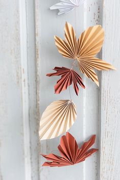 three folded paper flowers hanging from the side of a white door with rusted paint