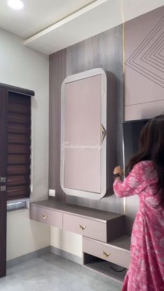 a woman standing in front of a dressing table with a mirror on top of it