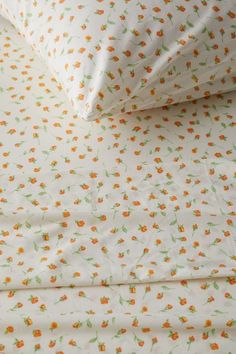 an orange flowered sheet set on top of a white bed cover with matching pillow cases