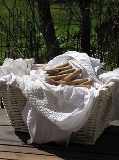 some bread sticks are in a wicker basket on a picnic table with white linens