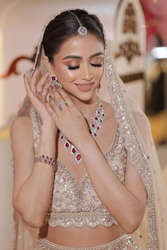 a woman in a bridal outfit with jewelry on her hands and wearing a veil