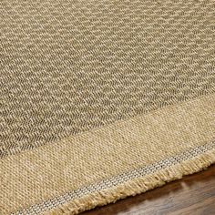 a close up view of a rug on the floor with brown carpeting and wood floors