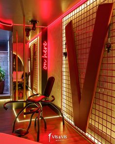 a room with red lighting and a chair in the corner, next to a mirror