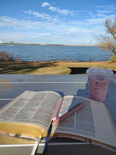 an open book sitting on top of a table next to a cup of coffee and a drink