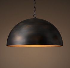 an industrial style pendant light hanging from a chain on a brown wall with a black background