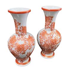 two orange and white vases sitting next to each other