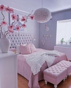 a bedroom decorated in pink and white with flowers hanging from the ceiling