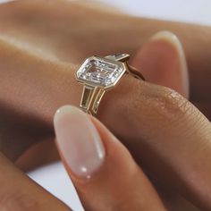 a woman's hand holding an engagement ring with a diamond on the top and side