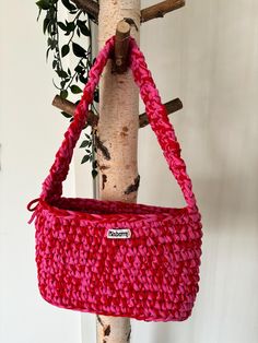 a pink bag hanging from a tree branch