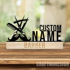 a wooden table topped with a sign that says custom name and barber scissors on it