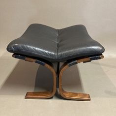 a black leather ottoman sitting on top of a wooden base