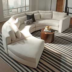 a living room with a large sectional couch and coffee table in the center, along with striped rugs