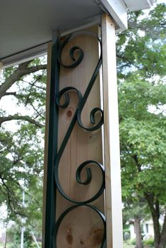 a close up of a wooden sign with wrought iron work on it's side