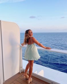 a woman standing on the deck of a cruise ship looking out at the ocean and smiling