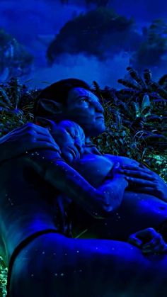 a woman holding a baby in her arms while floating on the ocean floor at night