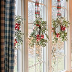 two wreaths hanging from the windows in front of them