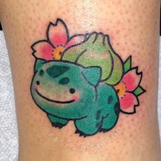 a small tattoo on the leg of a woman with flowers in her hair and a smiling frog