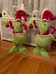 two green and red stuffed animals sitting on top of a wooden floor