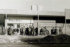 black and white photograph of people standing in front of a building