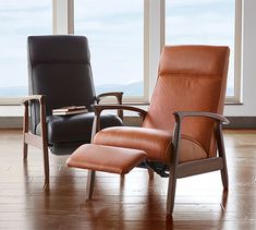 two leather recliners sit in front of large windows, one is brown and the other is black