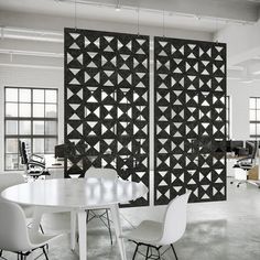 an office with white tables and chairs in front of two large black panels on the wall