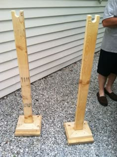 two wooden poles sitting on top of a gravel covered ground next to a white house