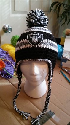 a knitted oakland football hat sits on top of a mannequin's head