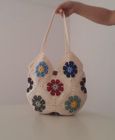 a hand holding a crocheted purse with flowers on it