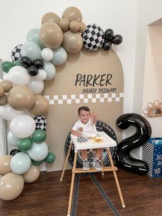 a baby sitting in a high chair next to balloons and a sign that says parker