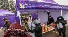 people are standing under a purple tent at an outdoor event with snow falling on them