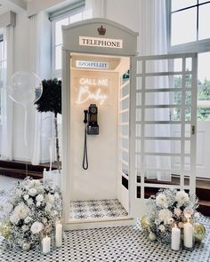 an old fashioned phone booth with flowers and candles