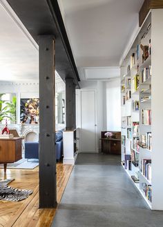 a long narrow hallway with bookshelves on both sides and zebra rugs on the floor