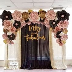 a black and white backdrop with pink flowers on the front, gold foil lettering that says fifty and fabulous