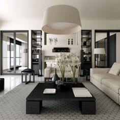 a black and white living room with couches, tables and lamps on the wall