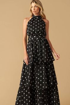 a woman wearing a black and white polka dot print dress with high low neckline