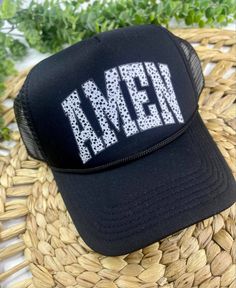 This all black trucker has has a mesh back, 100% polyester foam front, structured five-panels, mid-profile, pre-curved visor with braid detailing and a super cute black & white speckled "AMEN" message. Trendy Mesh Trucker Hat With Adjustable Fit, Trendy Adjustable Mesh Trucker Hat, Black Trucker Hat For Summer Sports, Black Trucker Hat With Curved Bill For Spring, Black Trucker Hat For Sports In Summer, Black Trucker Hat With Curved Bill For Baseball Season, Black Curved Bill Trucker Hat For Spring, Black Trucker Hat For Streetwear In Spring, Black Trucker Hat For Summer