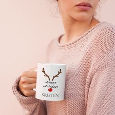 a woman is holding a coffee mug with reindeer antlers on it and the words happy holidays written in red