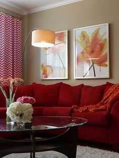 a living room with red couches and white flowers in vases on the coffee table