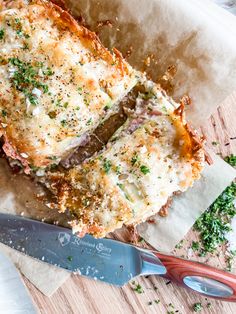 two slices of lasagna sitting on top of a cutting board next to a knife