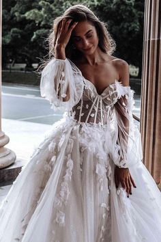 a woman posing in a white dress with flowers on the boudle and sleeves