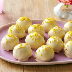 a pink plate topped with yellow sprinkles on top of a wooden table